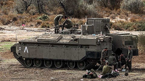 Israeli army soldiers sit by a deployed infantry-fighting vehicle (IFV) at a position along the border with Lebanon in northern Israel on 1 October 2024. The Israeli army on 1 October said it launched a ground offensive in Lebanon and that its forces engaged in clashes, further escalating the conflict after a week of intense air strikes that killed hundreds. The UN peacekeeping mission in Lebanon said, however, the Israeli operation did not amount to a "ground incursion" and while Hezbollah denied any troops had crossed the border, an Israeli security official said localised raids had taken place and they were limited in scope.