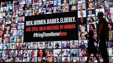 A man and a child walk past portraits of Israeli hostages held in Gaza since the October 7 attack by Hamas militants, in Tel Aviv on 21 November, 2023.