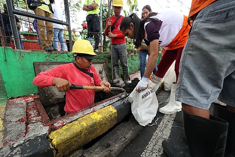 Workers of the Quezon City Department of Engineering remove sludge from a drainage.