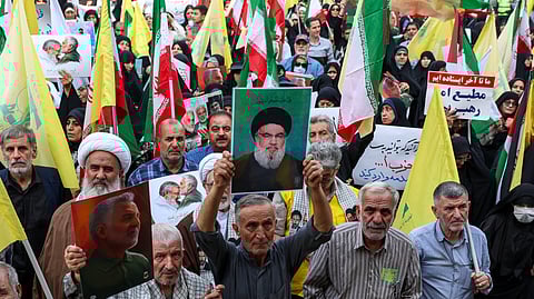 Iranians lift the flag of Hezbollah and a portrait of its slain leader Hassan Nasrallah during an anti-Israel rally in Tehran, on 8 October 2024. Iran warned Israel on 8 October against attacking any of its infrastructure amid fears of a possible Israeli assault on oil or nuclear sites following Iran's missile barrage last week. Tehran says its attack on Israel, when some 200 missiles were fired, was a response to the death in a Beirut air strike of Hassan Nasrallah, leader of the Iran-backed Lebanese movement Hezbollah, and of Hamas political leader Ismail Haniyeh in Tehran.