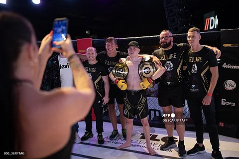 Mixed martial arts fighter Joe Frodsham (C) poses with his coaches and belts following his cage fight victory against Garon Shemar for the vacant 'GTFP 61.2kg Championship' at an evening of MMA combat hosted by 'Golden Ticket Fight Promotions' in Wolverhampton, central England, on September 7, 2024. Mixed Martial Arts fighting is a full-contact combat sport based on techniques of striking, throwing, kicking, and grappling with an opponent, often incorporating techniques from various combat sports including: boxing, wrestling, kickboxing and martial arts. Cage fighting events attract an international roster of fighters in both the amateur and professional categories.
Oli SCARFF / AFP
