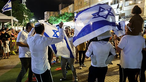 People dance and wave Israeli national flags as they celebrate the news of the death of Hamas leader Yahya Sinwar, in the Israeli coastal city of Netanya, on 17 October 2024. Israel said on 17 October its forces killed Sinwar, accused of masterminding the 7 October 2023 attack, calling it a "heavy blow" to the Palestinian group it has been fighting for more than a year.