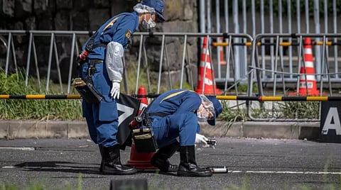 A police officer takes photographs of an object outside LDP headquarters in Tokyo on Saturday