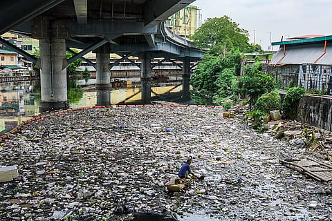 Scavenger collects recyclable plastics in San Juan River.