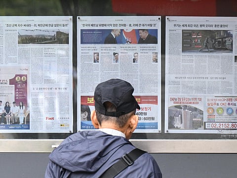 A man walks past a newspaper displayed on a street in Seoul on October 21 with coverage on North Korea's decision to deploy thousands of soldiers to Russia