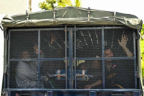 Global Ikhwan Services and Business Holdings’ (GISB) CEO Nasiruddin Mohd Ali (L) and other members wave to their family members from a police vehicle as they leave the Magistrate Court in Selayang, on the outskirts of Kuala Lumpur on October 23, 2024.