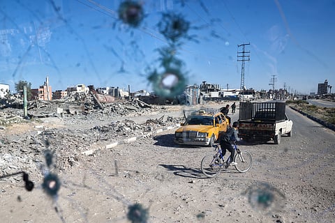 LOOK: People are seen through the shrapnel-riddled windscreen of a bus that was damaged when an Israeli artillery shell reportedly landed near it on Gaza's main Salah al-Din road outside Deir el-Balah in the central Gaza Strip on 24 October 2024, amid the ongoing war between Israel and Hamas. | Photo courtesy of Eyad BABA / AFP