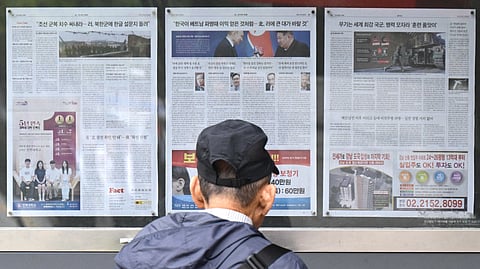 (FILES) A man walks past a newspaper displayed on a street for the public in Seoul on 21 October 2024, with coverage on North Korea's decision to deploy thousands of soldiers to Ukraine's front lines and a photo (C) of North Korean leader Kim Jong Un and Russia's President Vladimir Putin toasting at a banquet in Pyongyang earlier this year. North Korea has sent 1,500 more soldiers to Russia, Seoul's spy agency told lawmakers on 23 October 2024, with 10,000 troops expected to be deployed by December.