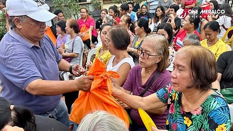 Volunteer from Meralco San Pablo Business Center hands relief bags to evacuees in Candelaria, Quezon.
