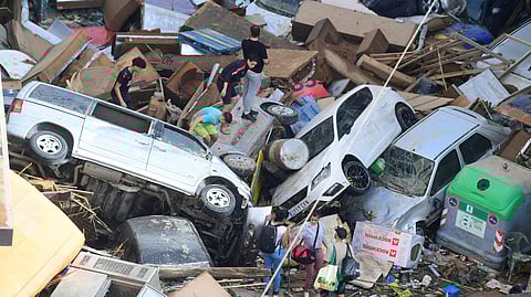 People climb on piled up cars following floods in Sedavi, south of Valencia, eastern Spain, on 30 October, 2024. Floods triggered by torrential rains in Spain's eastern Valencia region has left at least 70 people dead, rescue services said on 30 October.