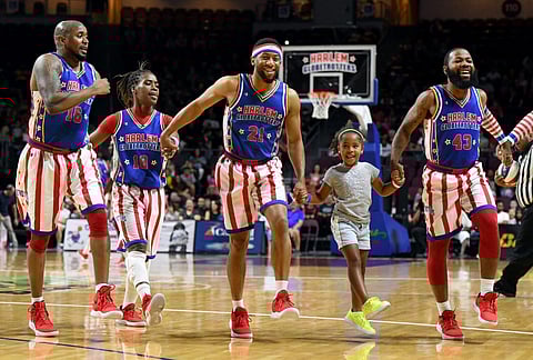 FILE–Gianna Burney, 6, skips across the court with (L-R) Shane “Scooter” Christensen #16, Fatima “TNT” Lister #18, Mike “Lights Out” Lee Jr. #21 and Darnell “Speedy” Artis #43 of the Harlem Globetrotters during the team’s exhibition game against the Washington Generals at the Orleans Arena on August 25, 2019 in Las Vegas, Nevada.