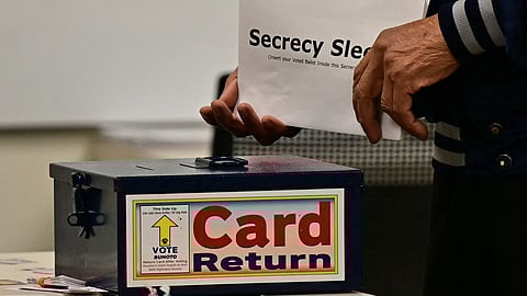 A voter carries his ballot card in a "secrecy sleeve" at a polling station at Las Vegas City Hall in Las Vegas, Nevada, on Election Day, 5 November 2024.
