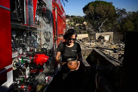 Robin Wallace carries a bowl of fish she saved from the pond of her family’s home on West Highland Drive after it was engulfed in flame and destroyed by the wind driven Mountain Fire wildfire on 8 November, 2024 in Camarillo, California. More than 130 homes are now known to have been destroyed by a raging wildfire burning outside Los Angeles, as a break in the weather on November 8 gave firefighters a chance to tame the blaze. Hurricane-strength winds that battered the area this week fuelled an explosion in the Mountain Fire near Camarillo, which grew rapidly to over 20,000 acres (8,000 hectares).