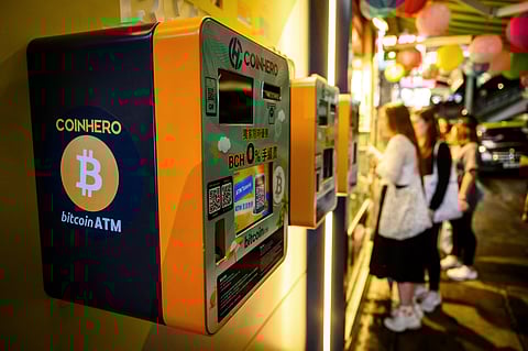 People stand next to bitcoin ATMs outside a cryptocurrency exchange in Hong Kong as the virtual money’s value is on an upswing due to an improved outlook on its acceptance under an administration of US President-elect Donald Trump.