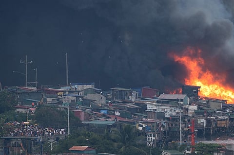 Flames and black smoke rise during a fire in the Isla Puting Bato residential area in Manila on 24 November, 2024.