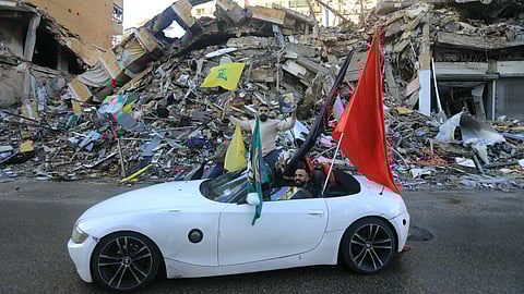 Driver waves the flag of Hezbollah as they parade in Beirut’s southern suburbs after a ceasefire between Israel and the Lebanese militant group took effect.