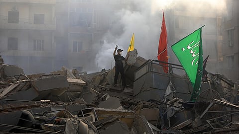 A man poses with Hezbollah banners on the rubble of a building flattened in an Israeli air strike that targeted Beirut's southern suburbs.