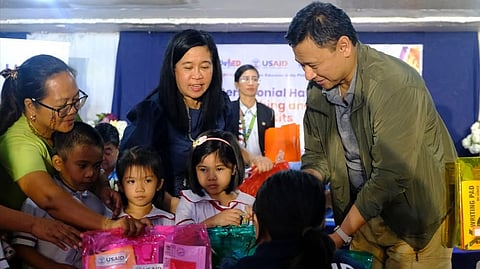 USAID hands over the educational materials to DepEd Secretary Juan Edgardo Angara (right) at Bula Central School in Camarines Sur on 2 December.