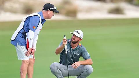 Cameron Young of the United States and his caddie, Steve Underwood, prepare for a shot on the 18th green during the first round of the Hero World Challenge 2024 at Albany Golf Course on Thursday in Nassau, Bahamas.