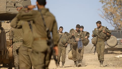 Israeli soldiers carry their belongings as they prepare for a military leave near their positions on the border with Lebanon on December 3, 2024.