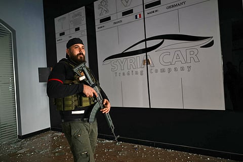 A rebel fighter stands guard in the building of the Syria Car Trading Company, belonging to Hafez Munther al-Assad, a relative of ousted Syrian president Bashar al-Assad, in the western port city of Latakia. Islamist-led rebels took Damascus in a lightning offensive, ousting president Bashar al-Assad and ending five decades of Baath rule in Syria.