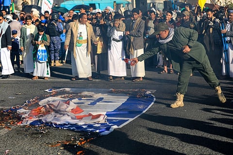 A man pours petrol on Israeli and US flags during a demonstration denouncing Israeli strikes and in solidarity with Palestine, in Yemen's Huthi-controlled capital Sanaa, on December 20, 2024. Yemen's Iran-backed Huthi rebels said Israeli air strikes on December 19 killed nine people, after the group fired a missile toward Israel, badly damaging a school.