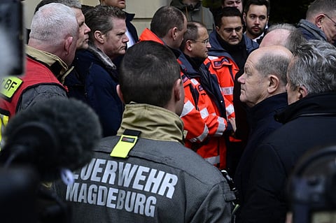 German Chancellor Olaf Scholz (R) talks to rescuers during a visit to the site of a car-ramming attack on a Christmas market in Magdeburg, eastern Germany, on 21 December, 2024, resulting in several deaths and dozens of injured. German media reports that the death toll has risen to four over night and up to 200 injured in the attack on 20 December.