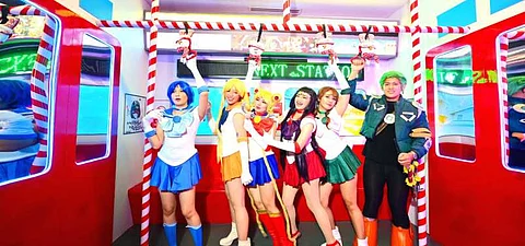 Cosplayers strike a pose inside a Christmas embellished train attraction.