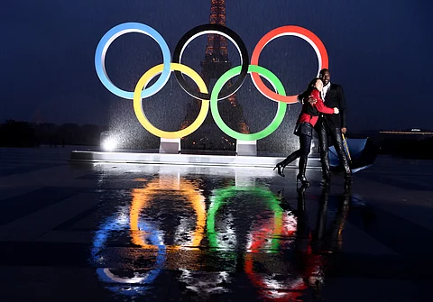 A couple poses in the rain ahead of the opening ceremony of the Paris Olympics.
