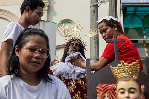 Devotees begin early with the ritual of wiping a handkerchief on a replica of the Jesus Nazareno outside the Minor Basilica of Quiapo. This act of veneration marks their preparation for the upcoming religious festivity on 9 January, which is expected to draw millions of believers to honor the revered icon.