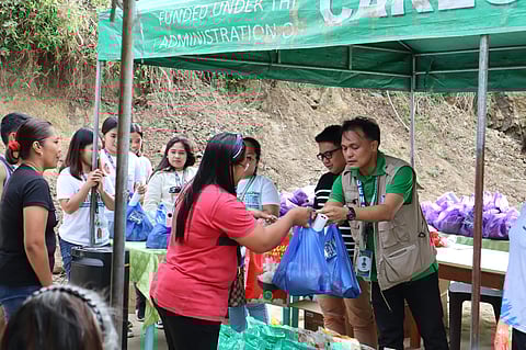 DENR and OceanaGold volunteers hand food packs to residents of Malasin.