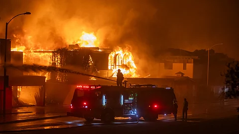 LOS ANGELES, CALIFORNIA - JANUARY 8: Firefighters battle the Palisades Fire while it burns homes on the Pacific Coast Highway amid a powerful windstorm on 8 January 2025 in Los Angeles, California. The fast-moving wildfire has grown to more than 2900-acres and is threatening homes in the coastal neighborhood amid intense Santa Ana Winds and dry conditions in Southern California.