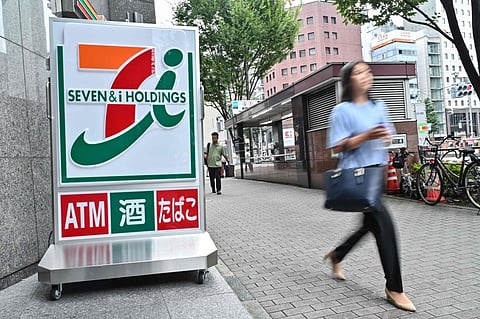 A woman walks out of a 7-Eleven convenience store along a street in central Tokyo on August 22, 2024.