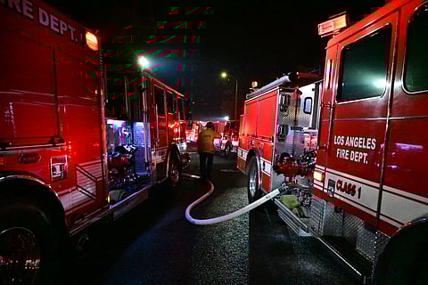 Multiple firetrucks are seen in a narrow residential street as the Sunset Fire burns near Hollywood Blvd in the Hollywood Hills in Los Angeles, California, on January 8, 2025. At least five people have been killed in wildfires rampaging around Los Angeles, officials said on January 8, with firefighters overwhelmed by the speed and ferocity of multiple blazes -- including in Hollywood.