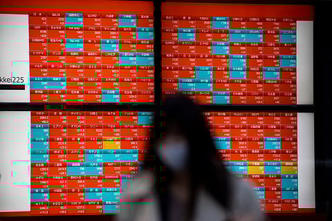 A pedestrian wearing a face mask walks past an electronic board displaying closing numbers of share prices of Tokyo EStock Exchange in Tokyo on 9 November 2020, as Asian markets react to the results of the US presidential election.