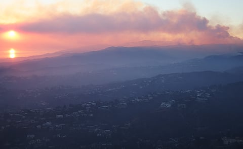 In an aerial view, the Palisades Fire continues to burn as the sun sets on 9 January 2025, near Pacific Palisades, California. Multiple wildfires fueled by intense Santa Ana Winds are burning across Los Angeles County. At least five people have been killed, and over 25,000 acres have burned. Over 2,000 structures have also burned and almost 180,000 people are under orders to evacuate.