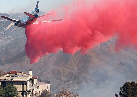 Califerno California Fire Department helicopter drops water next to a building near hillsides scorched by the Palisades Fire in Topanga, California. Massive wildfires that engulfed whole neighborhoods and displaced thousands in Los Angeles have killed at least 10 people.