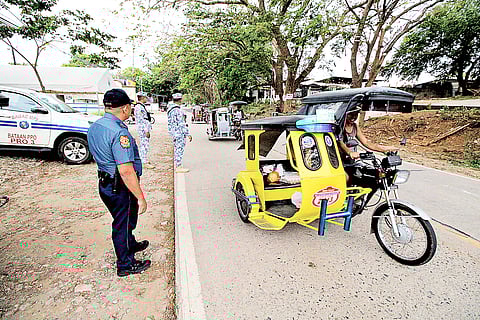 POLICE officers check incoming vehicles at a Comelec checkpoint in Bagac, Bataan on Sunday. The PNP has intensified its checkpoint operations all over the country in preparation for the upcoming national and local elections in May.