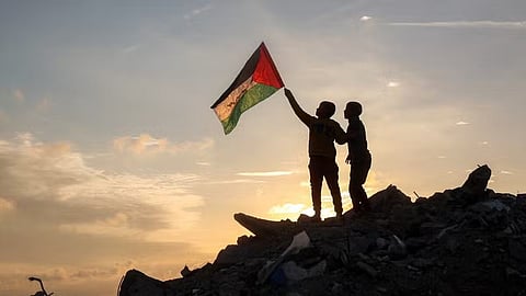 A boy runs with a Palestinian flag atop a mound of rubble at a camp for people displaced by conflict in Bureij in the central Gaza Strip on January 17, 2025 following the announcement of a truce amid the ongoing war between Israel and Hamas.