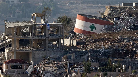 (FILE PHOTO) An Israeli flag on a destroyed building, and a Lebanese flag painted on a damaged building in the southern Lebanese village of Meiss El-Jabal on November 25, 2024.