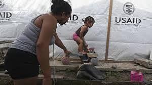 Sandra Ramos plays with her daughterat an improvised shack built with the help of the US Agency for the International Development (USAID) following hurricanes in in La Lima, Honduras, in July 2022