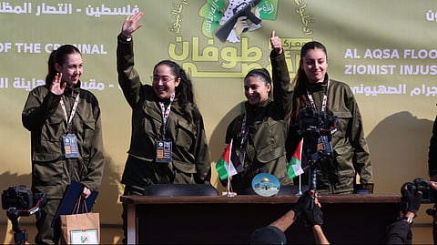 Four Israeli hostages, (L-R) Naama Levy, Liri Albag, Daniella Gilboa and Karina Ariev, wave from a stage before Hamas fighters hand them over to a team from the Red Cross in Gaza City on 25 January 2025. Four freed Israeli women hostages were home in Israel 25 January, ending more than 15 months of captivity after Hamas militants handed them over to the Red Cross under a truce deal in the Gaza war.