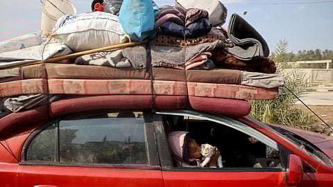 A displaced Palestinian child playes with a kitten in a car on Salah al-Din road in Nuseirat as people make their way to the north of the Gaza Strip