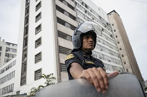 A police officer looks on as he stands guard at the National Prosecutor’s headquarters building in Lima before the arrival of Peruvian President Dina Boluarte in Lima on 13 January 2025. The president of Peru, Dina Boluarte, appears this Monday before prosecutors investigating her for the alleged crime of abandonment of office and omission of functional acts, due to the fact that she did not inform the ministerial cabinet and Congress that she would undergo a nose job in July 2023.