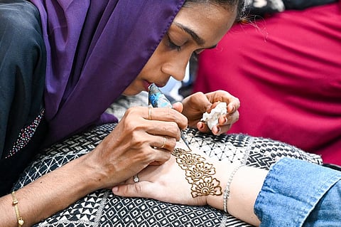 An artist draws a henna tattoo on a customer's hand ahead of Eid al-Fitr, which marks the end of the Muslim holy fasting month of Ramadan, at Geylang Serai bazaar in Singapore on 9 April 2024.