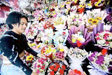 Symphony of petals A flower vendor carefully arranges vibrant bouquets at Araneta City, Cubao, Quezon City, as love blossoms Thursday on the eve of Valentine’s Day.