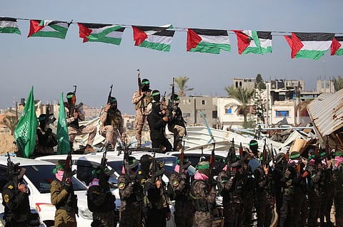 Palestinian Hamas fighters secure an area before handing over Israeli hostages by his group to a Red Cross team in Khan Yunis in the southern Gaza Strip on 15 February 2025, as part of the sixth hostage-prisoner exchange. Gaza militants are due to release three Israeli hostages on February 15 in exchange for 369 Palestinians in Israeli custody, the latest swap of a truce that came close to collapse this week.