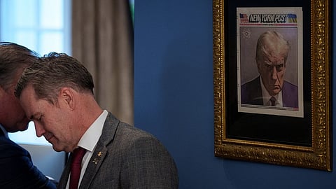 A copy of U.S. President Donald Trump's mugshot on the front of the New York Post is framed in an office just outside the Oval Office as U.S. National Security Adviser Michael Waltz speaks with someone at the White House on 14 February 2025 in Washington, DC.