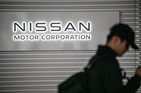 This file photo taken on 10 February 2025 shows a man walking past the Nissan logo in the showroom at Nissan's global headquarters in Yokohama, Kanagawa prefecture.