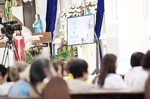 Catholic devotees offer prayers for the healing of Pope Francis as his portrait is displayed on a video screen at a church in Manila on 20 February 2025.